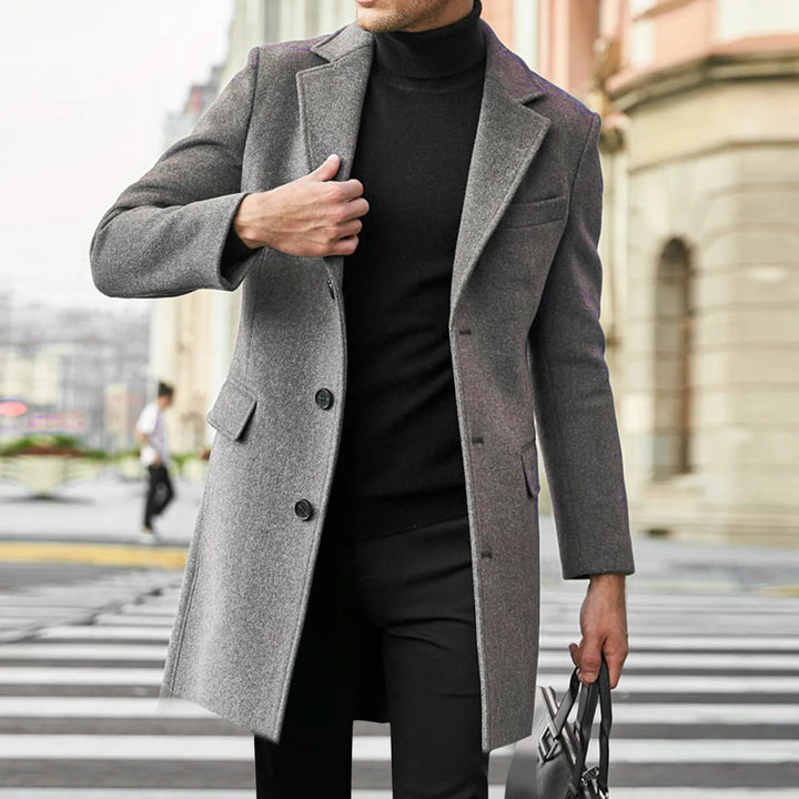 Man wearing grey men's tailored overcoat with notched lapel and button closure on city street