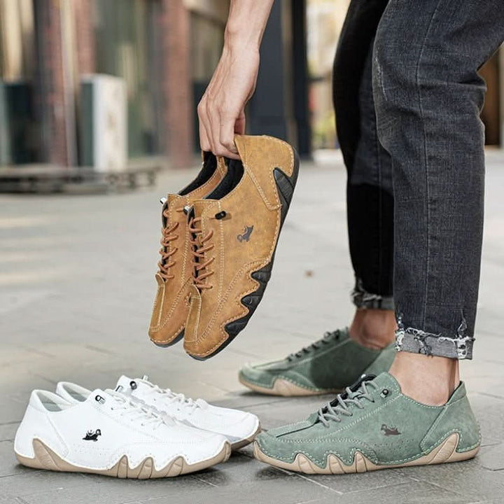 Men's tan trainers with lace-up closure worn with distressed jeans on outdoor pavement