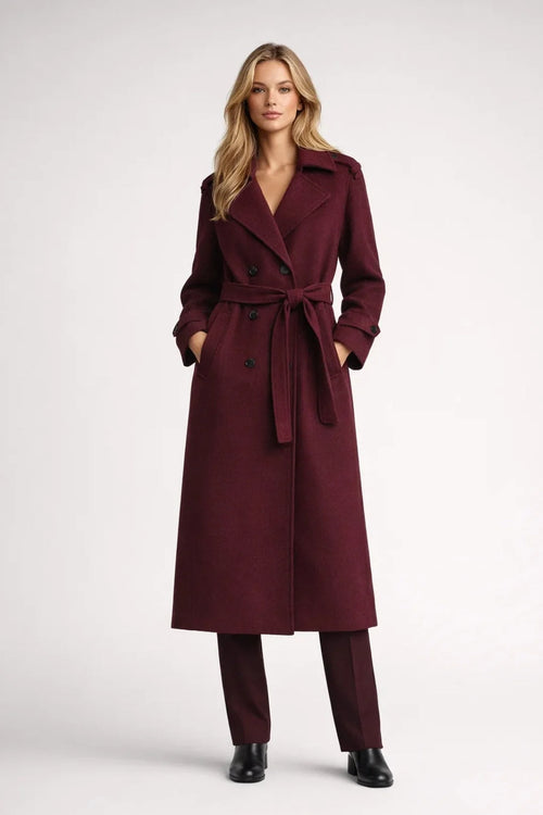 Women's long burgundy trench coat with double-breasted closure and tie belt, ankle-length silhouette with notched lapels