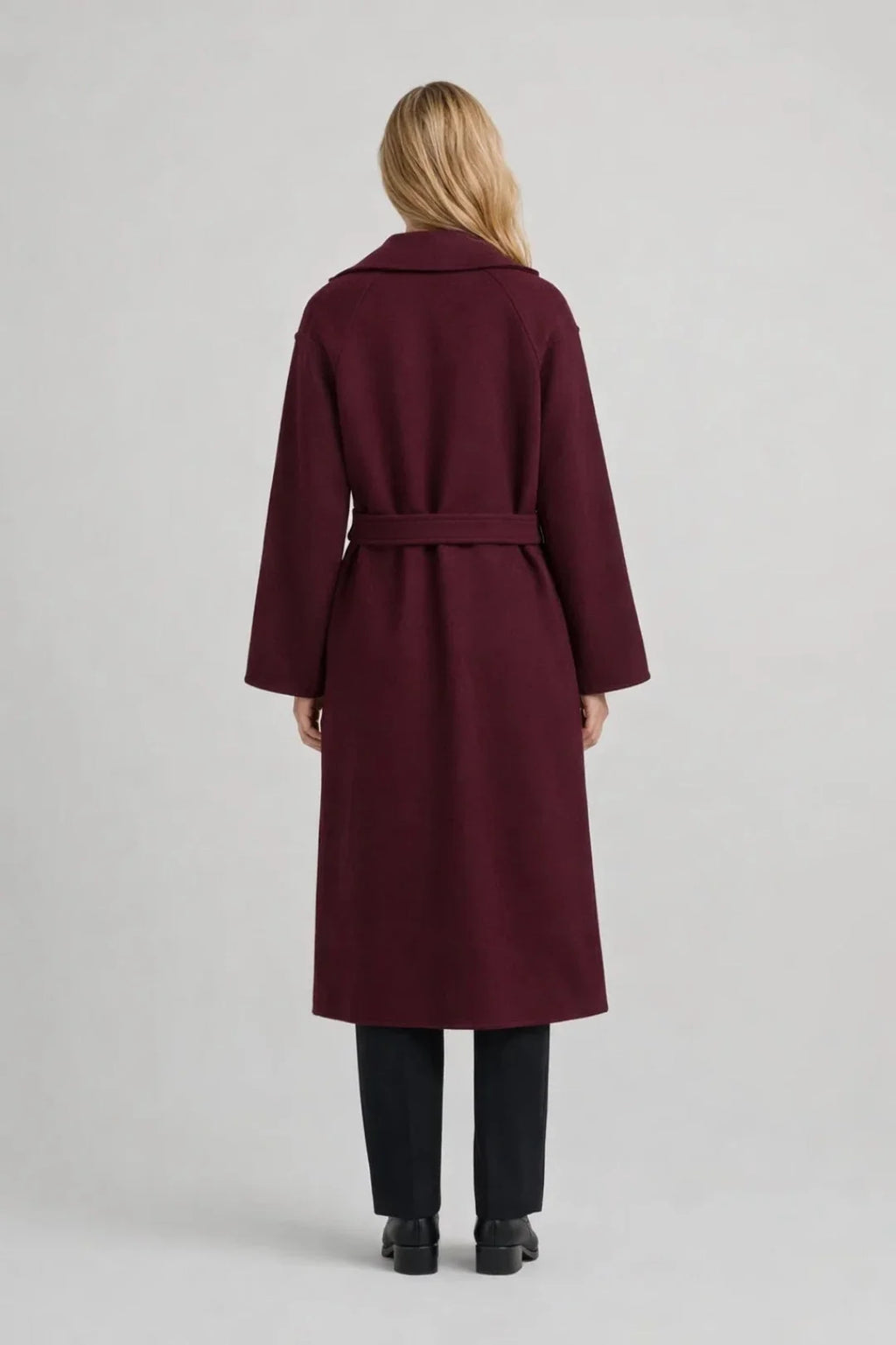 Close-up view of women's burgundy trench coat showing double-breasted button detail and self-tie waist belt