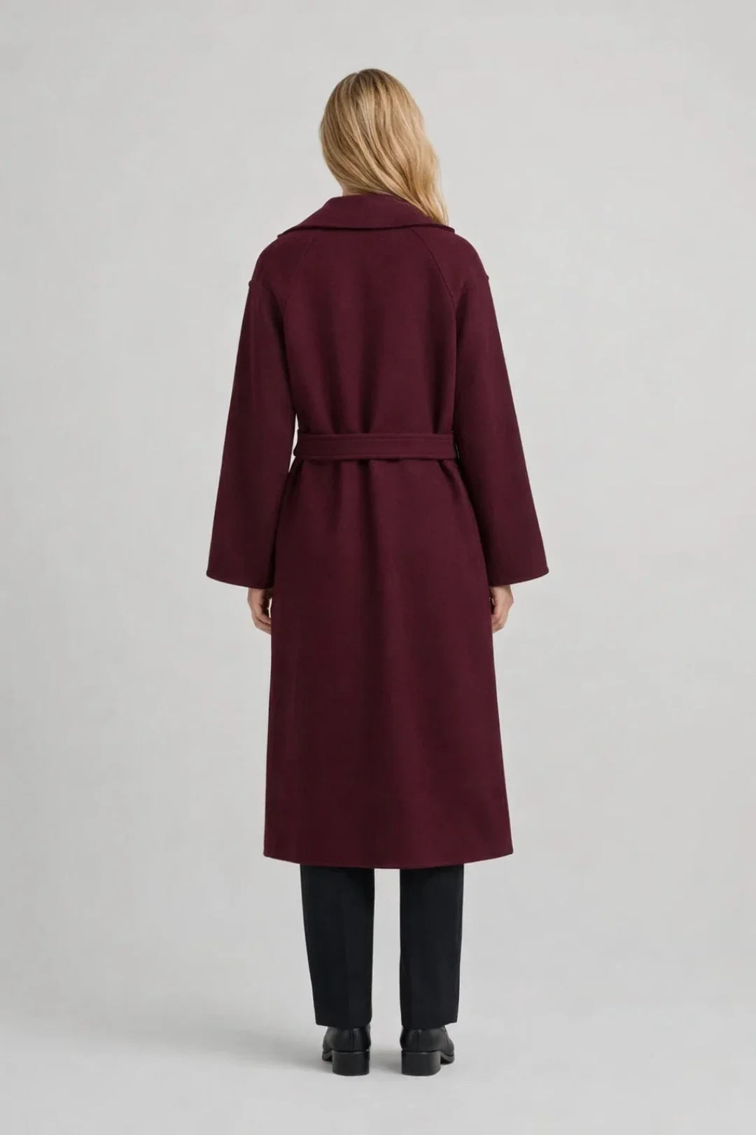 Close-up view of women's burgundy trench coat showing double-breasted button detail and self-tie waist belt