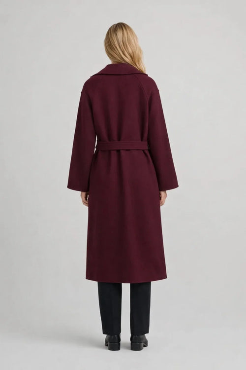 Close-up view of women's burgundy trench coat showing double-breasted button detail and self-tie waist belt