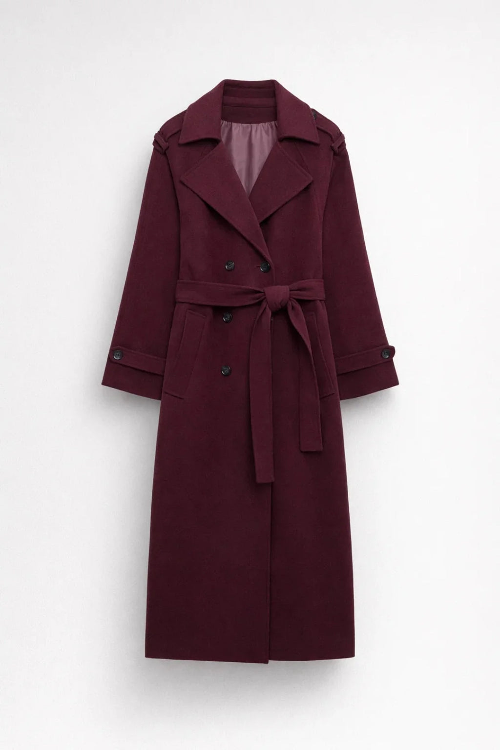 Full-length women's burgundy trench coat styled with black trousers and ankle boots for autumn layering