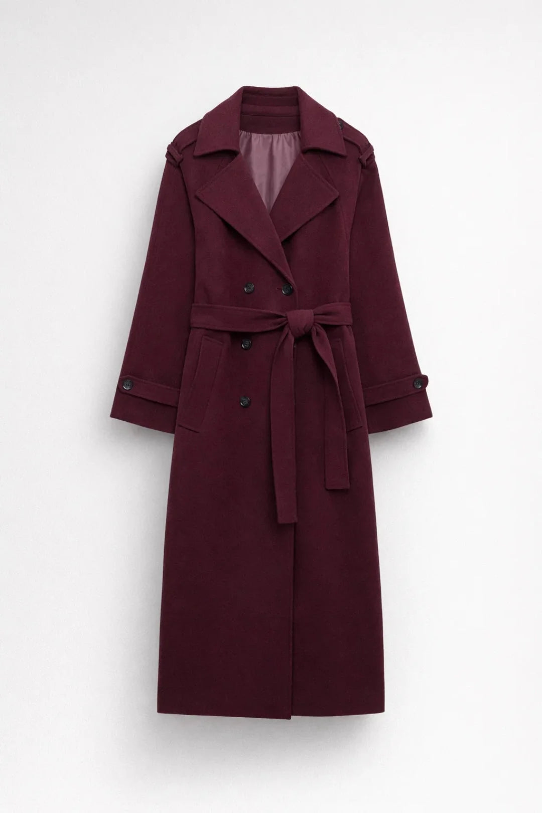 Full-length women's burgundy trench coat styled with black trousers and ankle boots for autumn layering