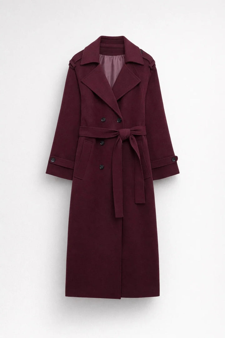 Full-length women's burgundy trench coat styled with black trousers and ankle boots for autumn layering
