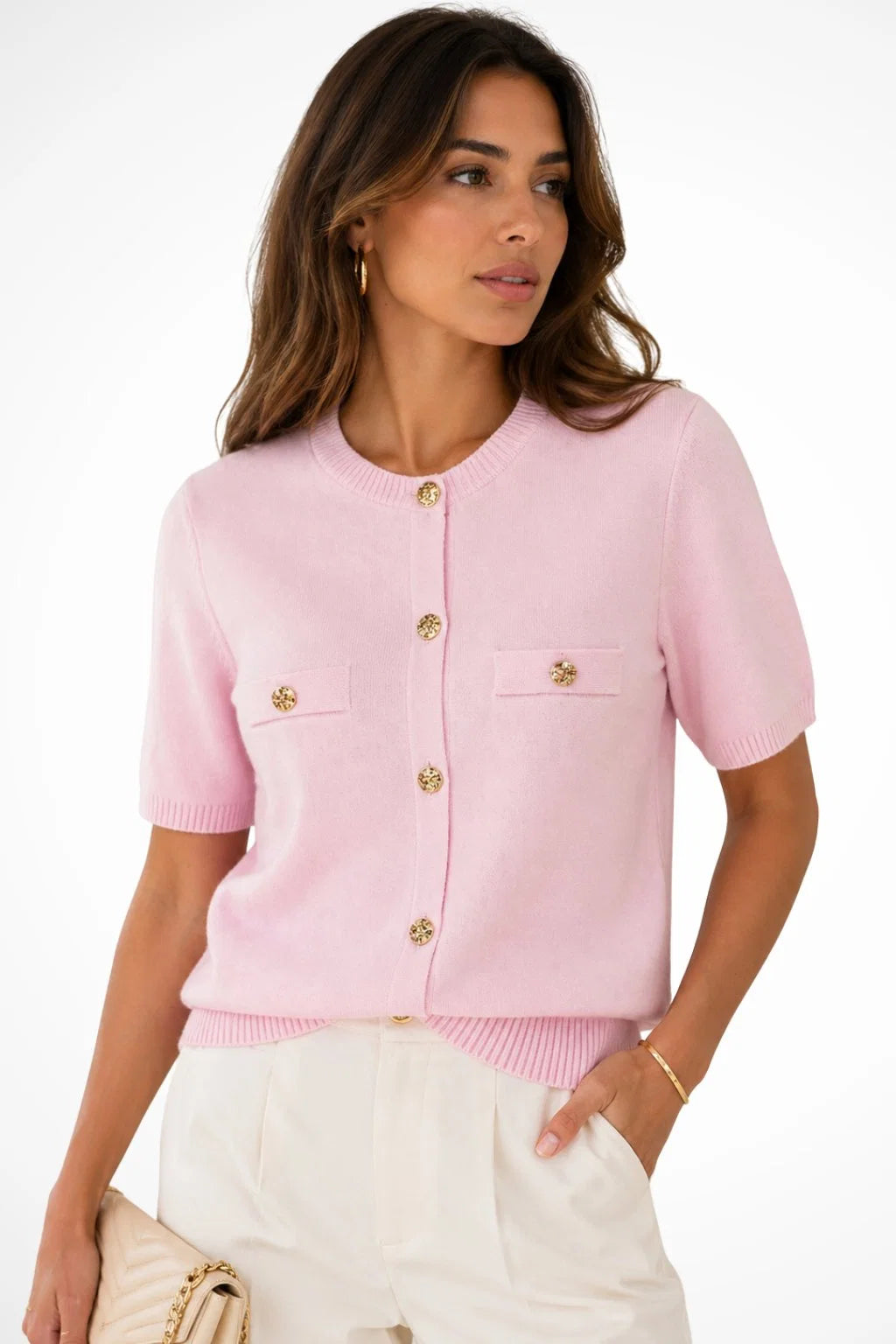 Woman wearing a pink short sleeve knit cardigan with gold button detail and chest pockets