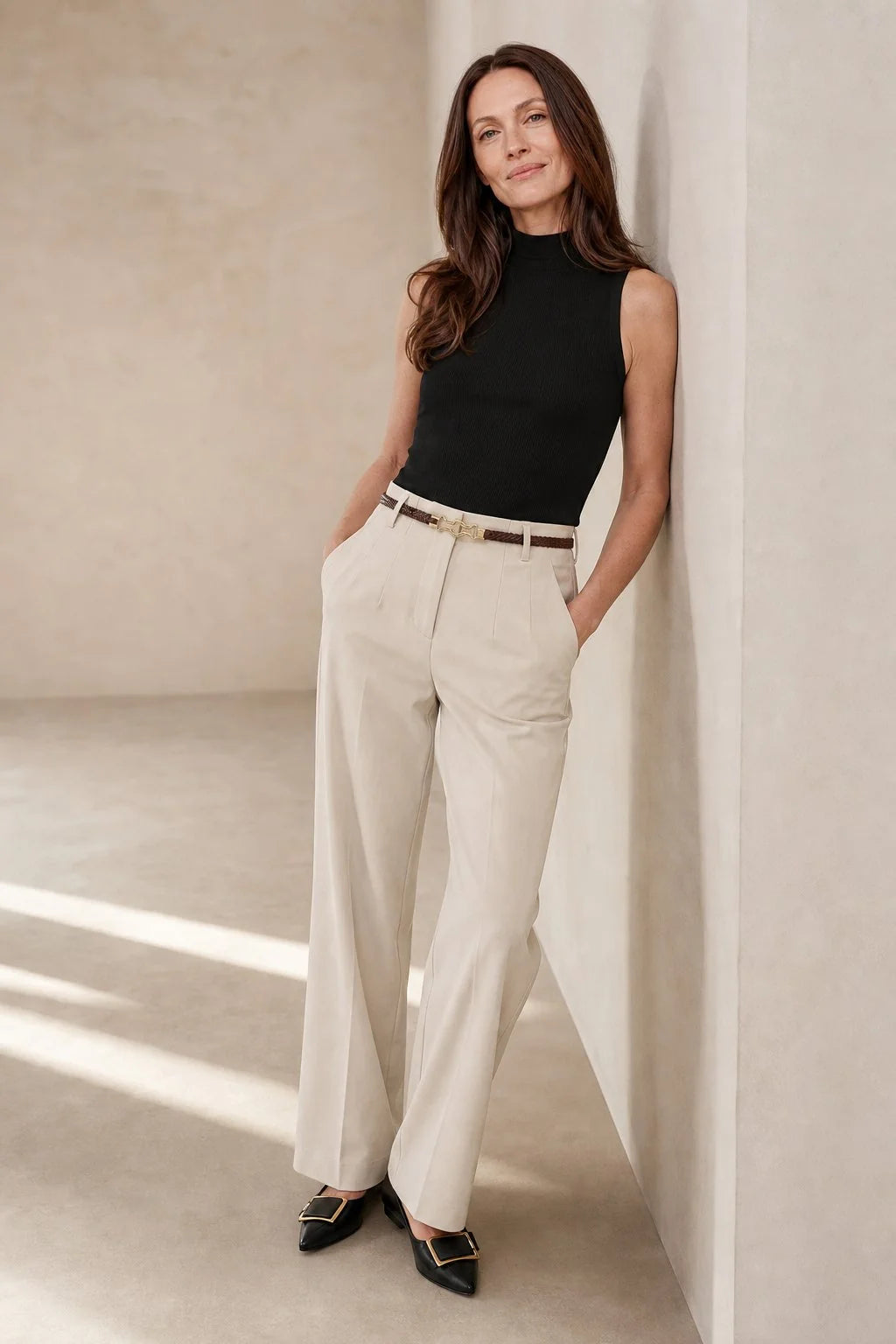 Close-up of beige wool trousers showing wide leg silhouette and pressed front creases with belt loops
