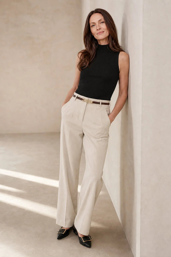 Close-up of beige wool trousers showing wide leg silhouette and pressed front creases with belt loops