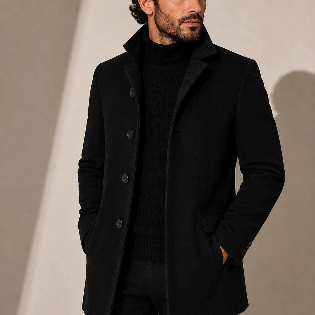 Men's tailored coat with stand collar and button-front closure in solid black worn over turtleneck