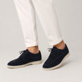 Men's navy suede loafers with lace-up design styled with white trousers for smart casual wear