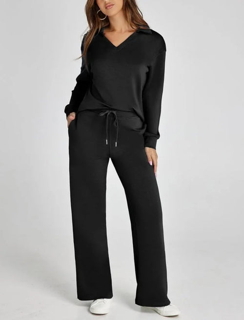 Women's lounge set with V-neck top and wide-leg trousers in black, worn with white trainers for casual styling