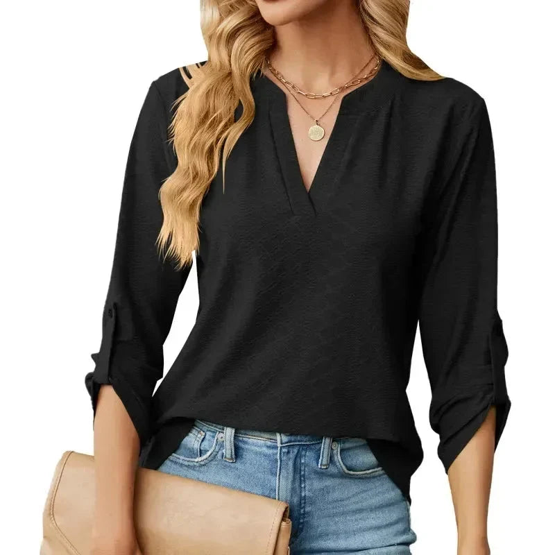 Women's V-neck blouse with textured fabric and roll-up sleeves in black, styled with jeans