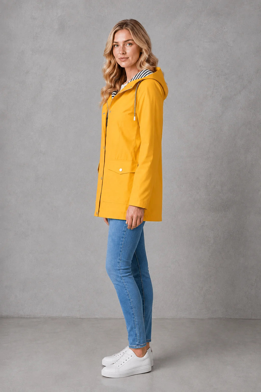 Yellow hooded raincoat for women featuring patch pockets and mid-thigh length with water-resistant finish