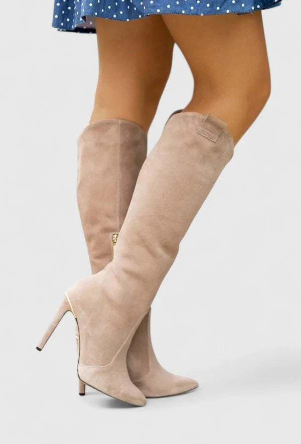 Women's knee-high heeled boots styled with midi skirt showing full shaft length and elegant design