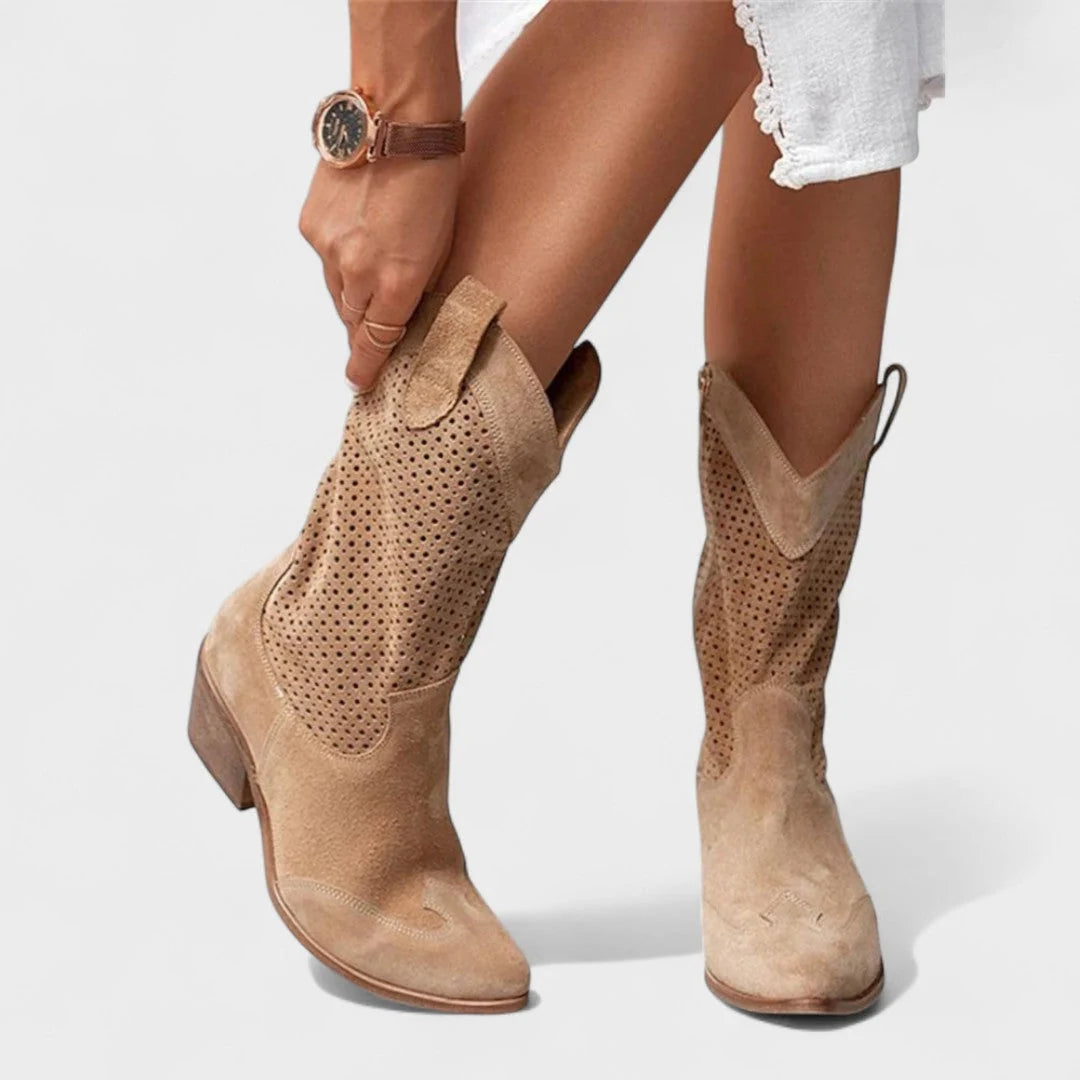 Women's perforated cowboy boots in beige with block heel and Western-inspired silhouette, styled with white shorts.
