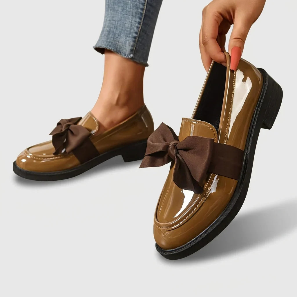 Women's bow detail loafers with glossy patent finish and chunky block heel on model