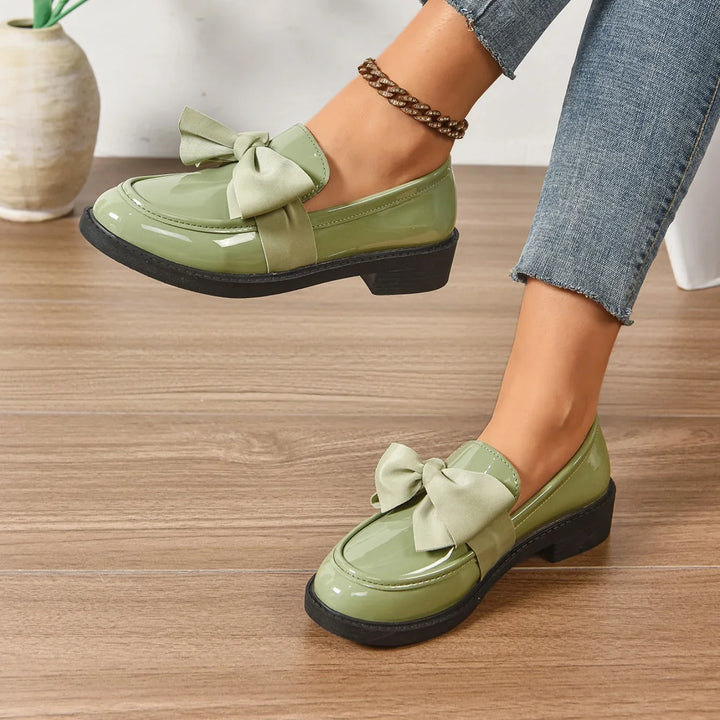 Side angle of patent loafers showing block heel and structured upper