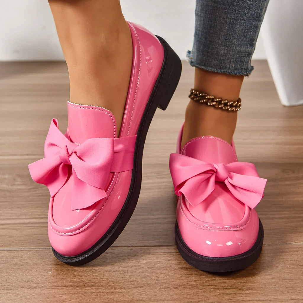 Full view of bow detail loafers showing glossy upper and block heel
