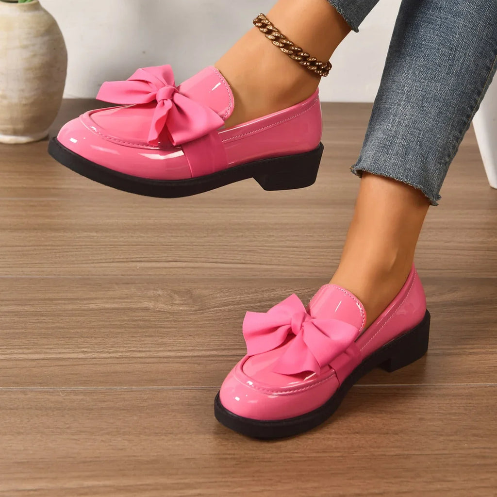 Patent loafers with decorative bow worn with casual outfit on model