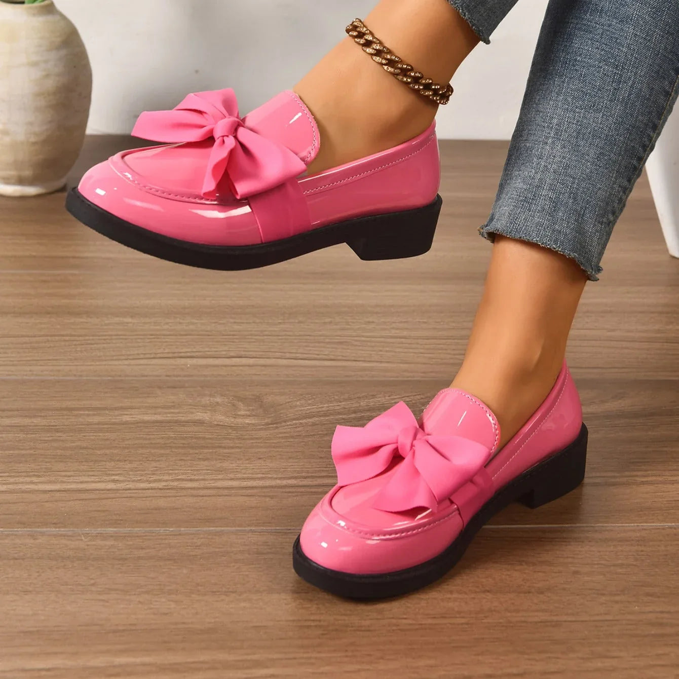 Patent loafers with decorative bow worn with casual outfit on model