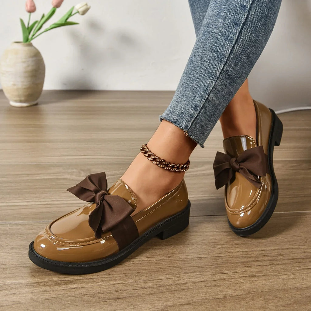 Front view of women's patent loafers with chunky sole and bow accent