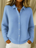 Woman wearing blue collared knit cardigan with button-through front and ribbed texture over white trousers
