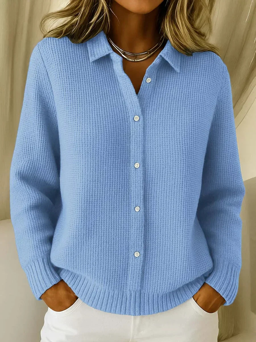 Woman wearing blue collared knit cardigan with button-through front and ribbed texture over white trousers