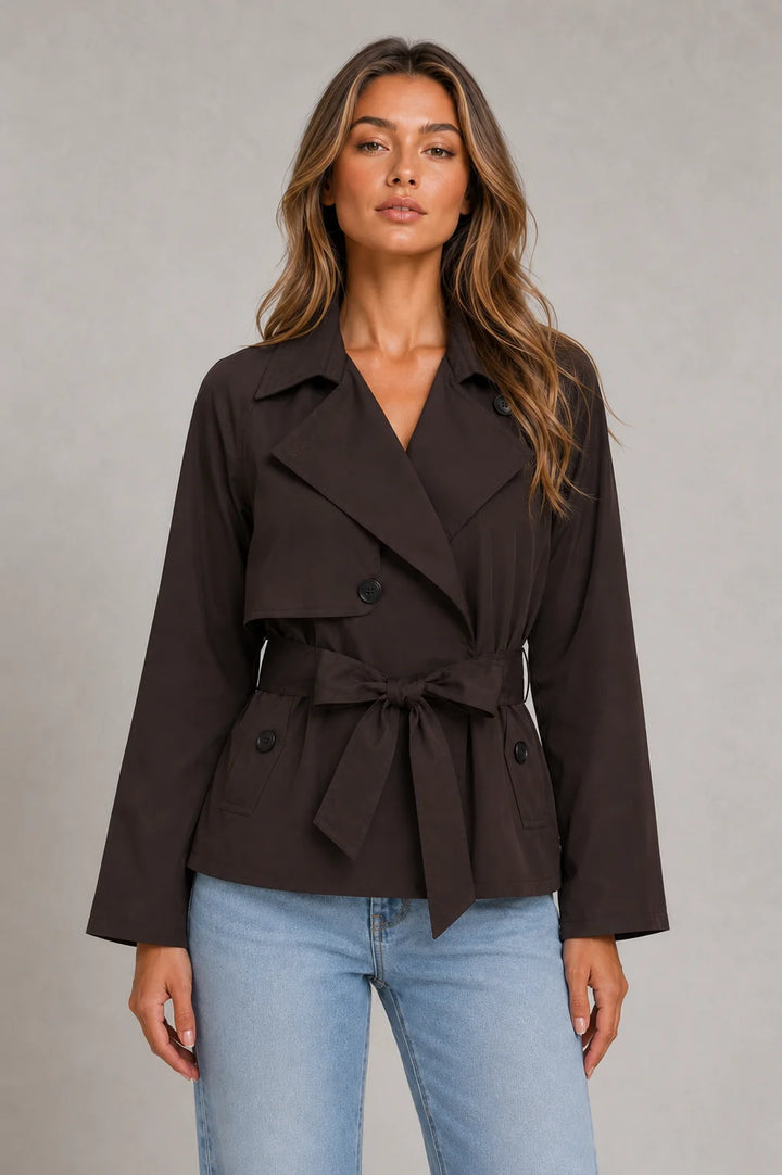 Back view of beige cropped trench jacket showing structured shoulders and cropped hemline at hip level