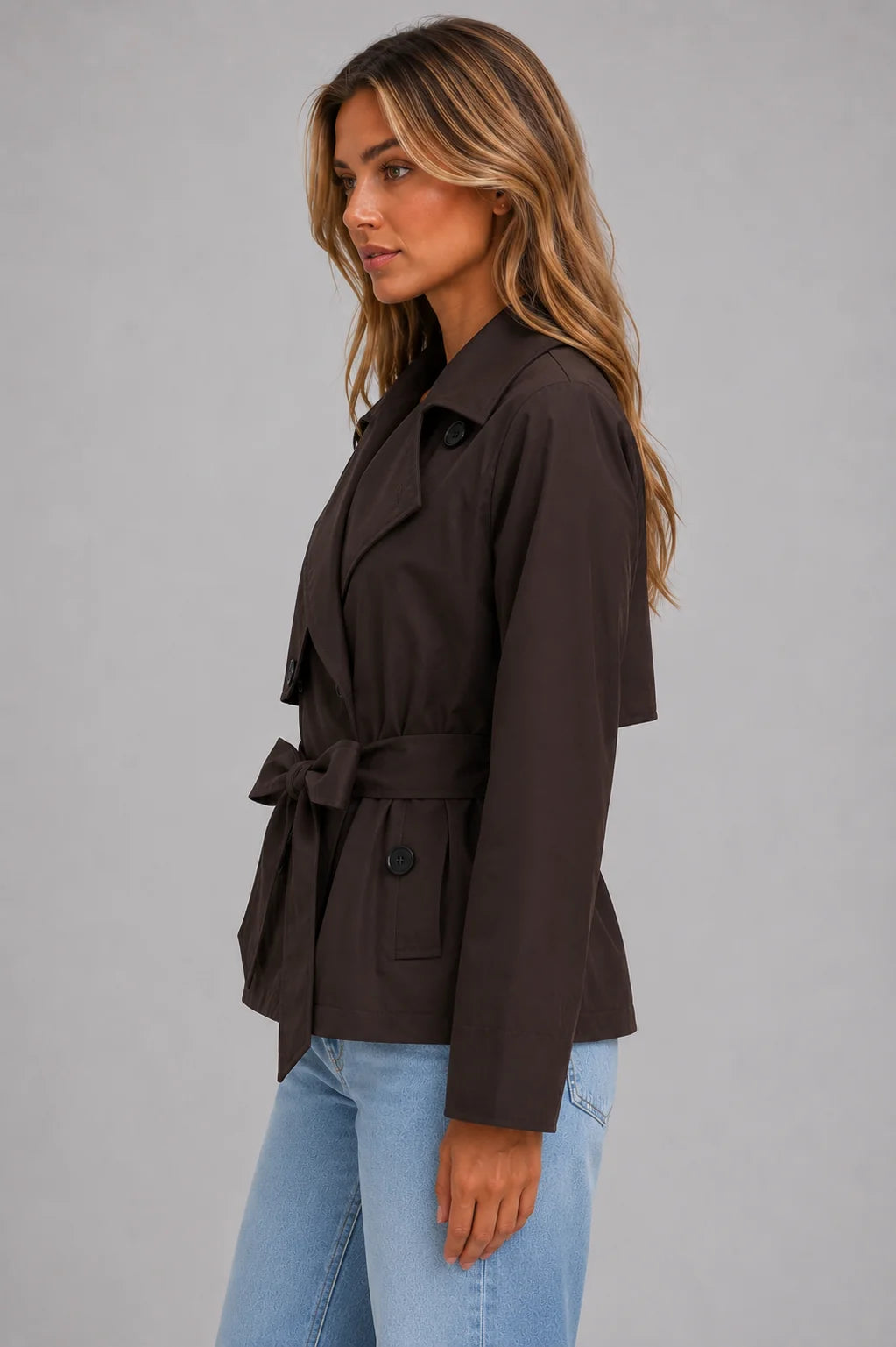 Detail shot of self-tie waist belt and functional side pocket on women's cropped trench jacket
