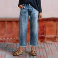 Woman wearing cropped wide-leg jeans with high waist and distressed wash, paired with sandals