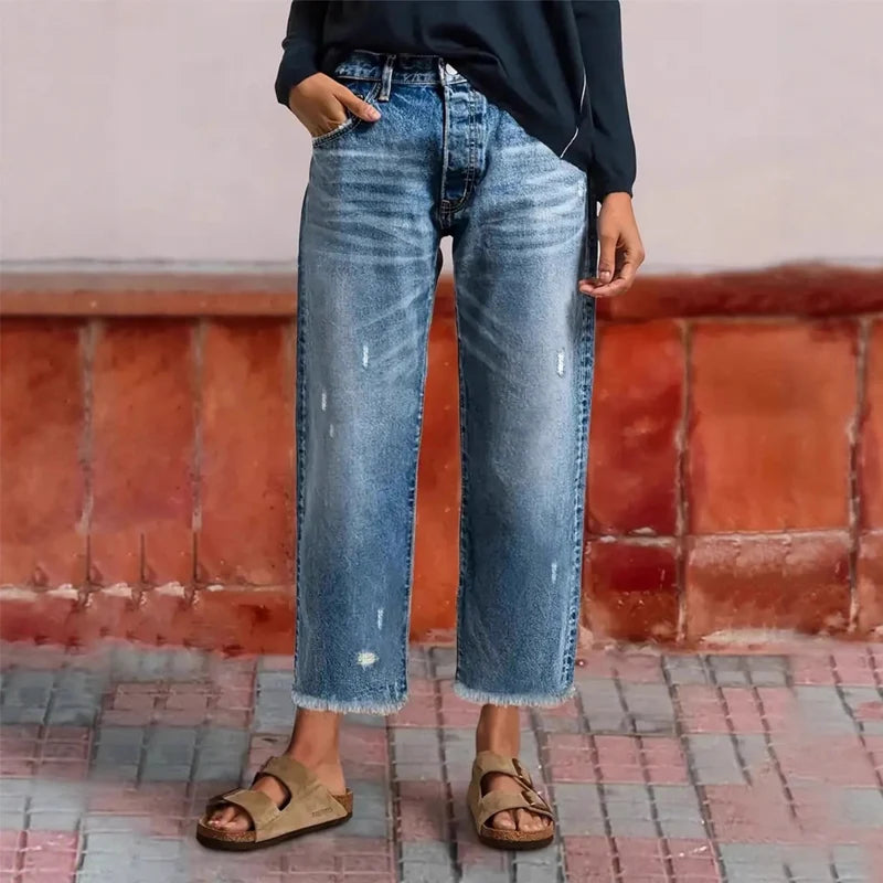 Woman wearing cropped wide-leg jeans with high waist and distressed wash, paired with sandals