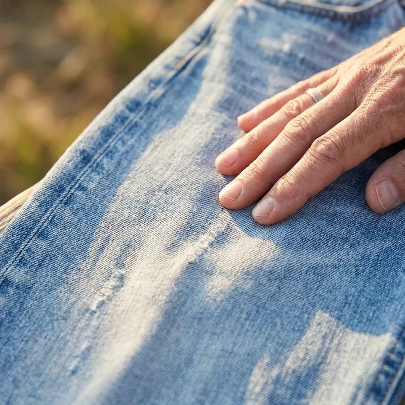 Detail shot of raw-edge hem on cropped denim jeans with distressing