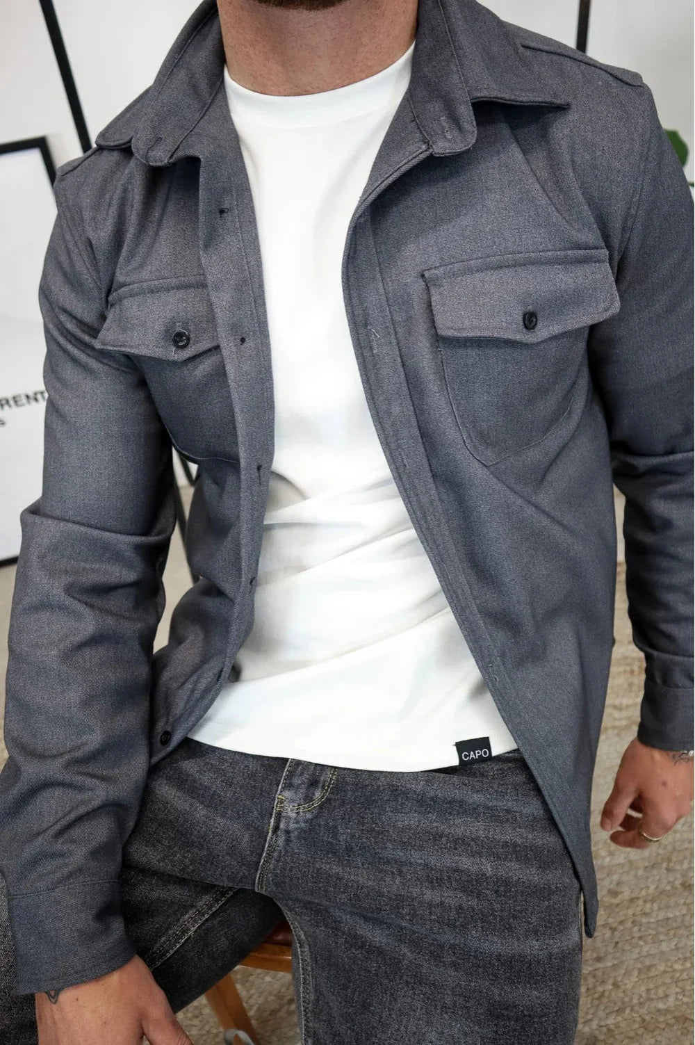 Detail shot of chest pocket with button flap closure on men's casual overshirt
