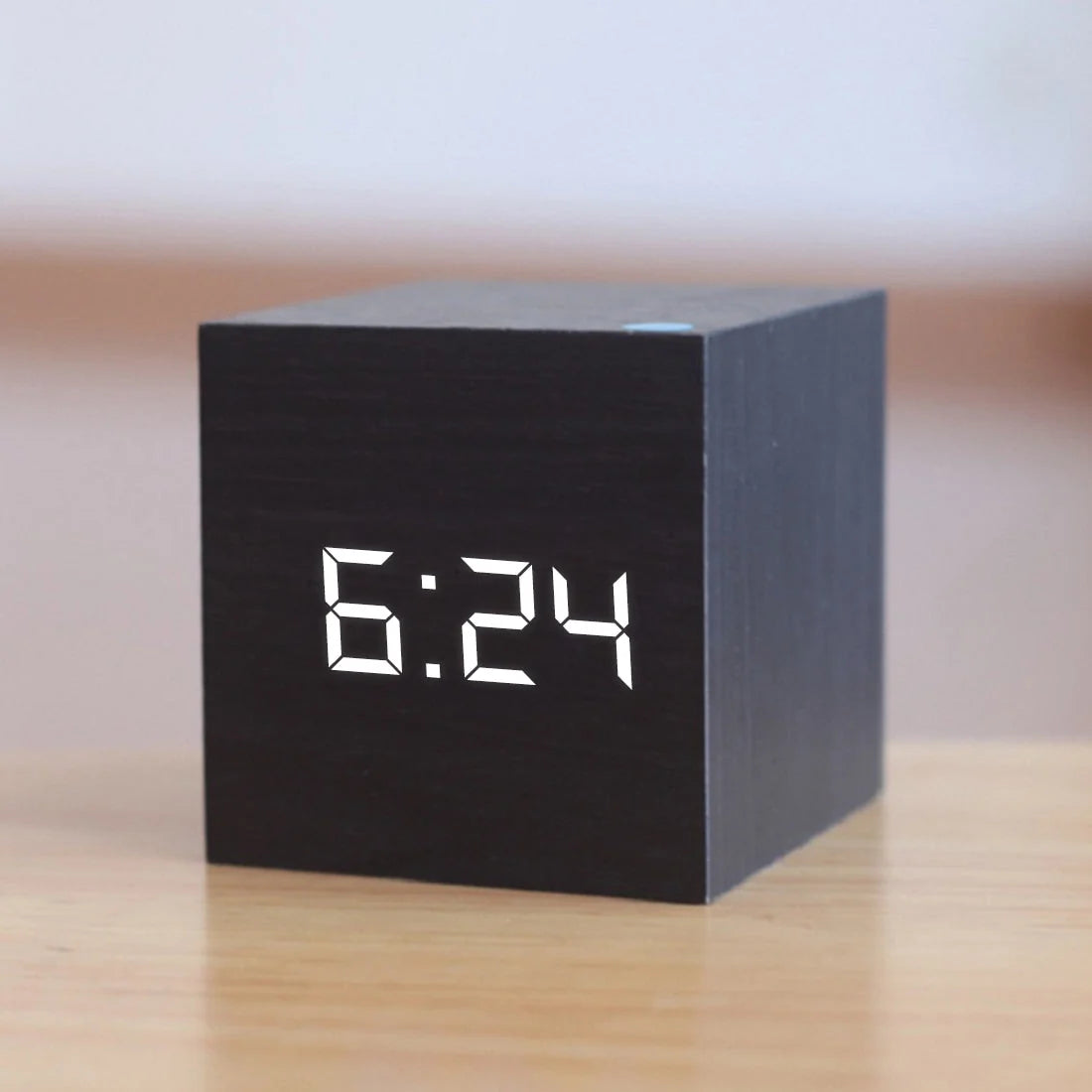 Men's digital cube alarm clock with LED display showing time on wooden desk surface
