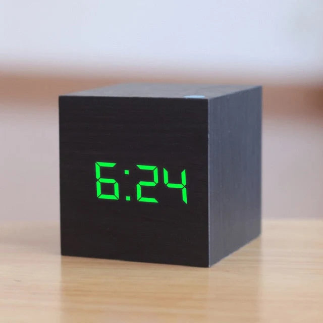 Compact cube alarm clock displaying digital time in bright LED segments on bedside table