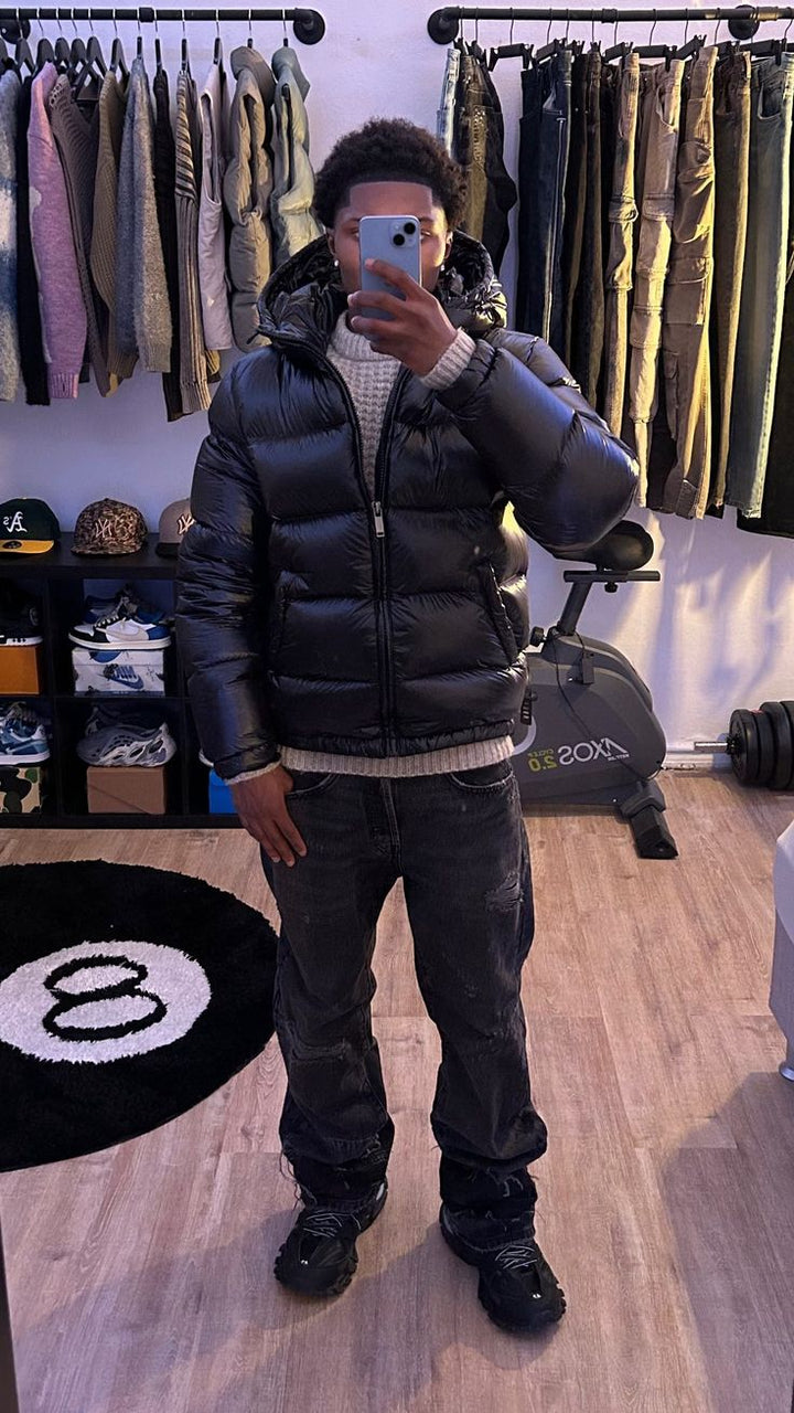 Full-body shot of black quilted puffer jacket showing relaxed fit and dropped shoulder seam detail