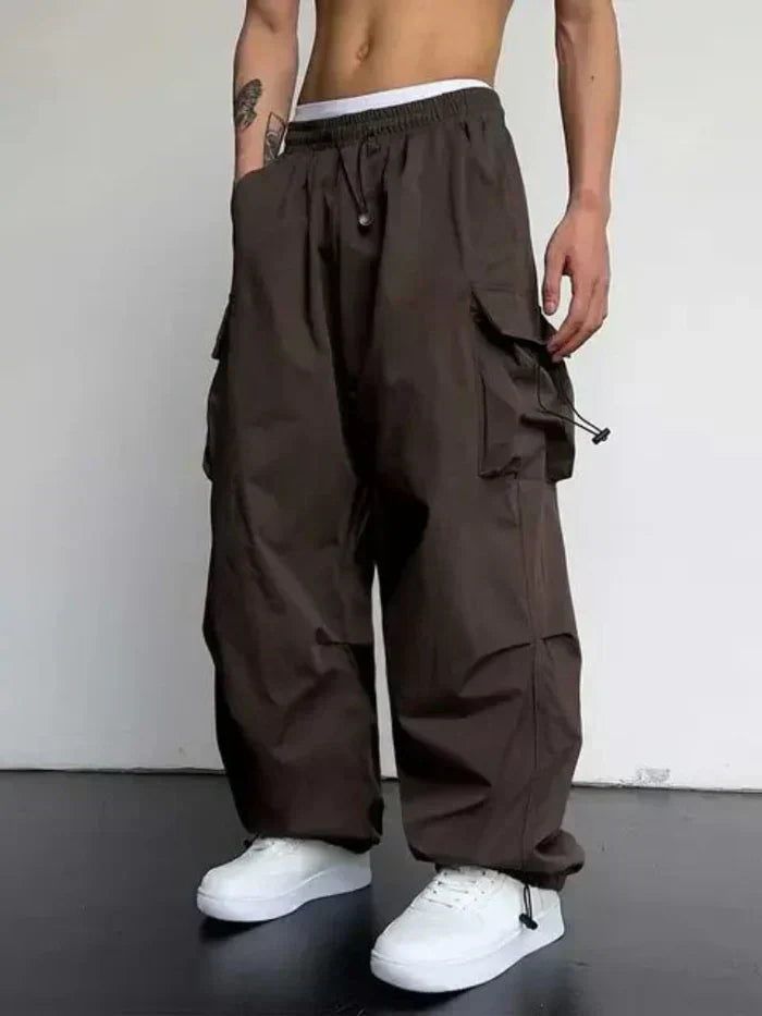 Side view of men's black cargo trousers showing wide leg silhouette and cargo pocket detail