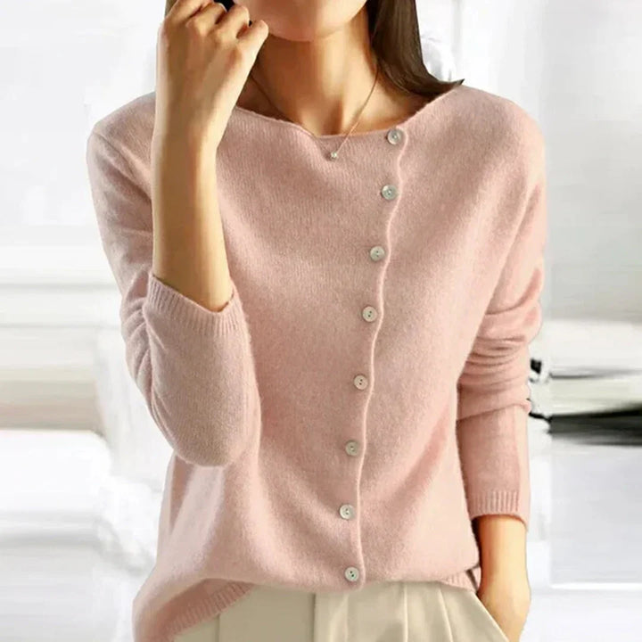 Women's knit cardigan with asymmetric button front and scoop neckline in soft pink worn over cream trousers