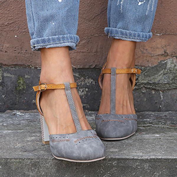 Full view of women's ankle strap block heel shoes in navy and tan colourway on textured surface