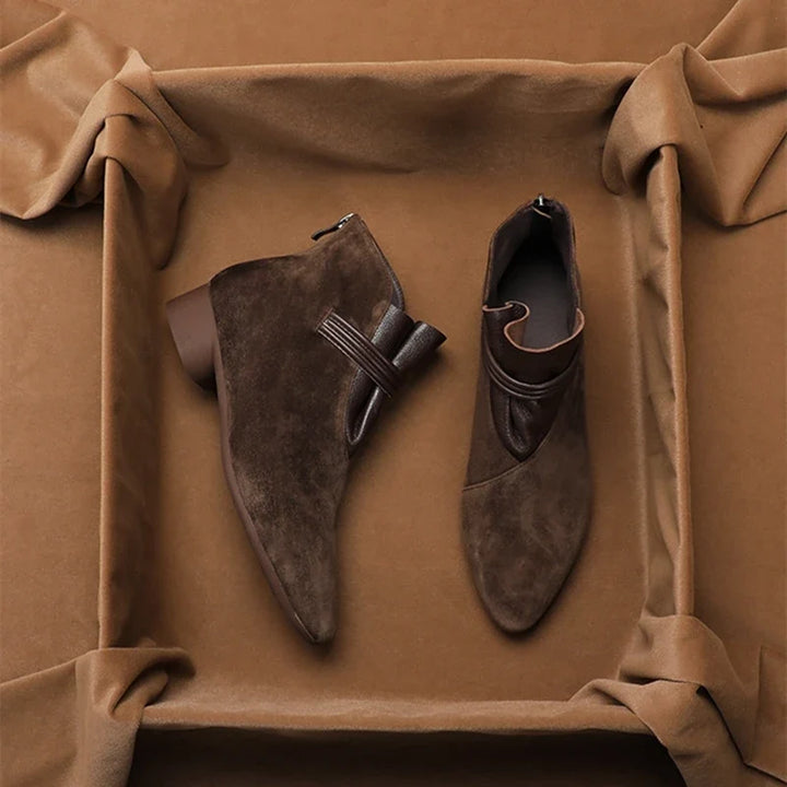 Three-quarter view of pointed-toe suede ankle boots in dark brown shade