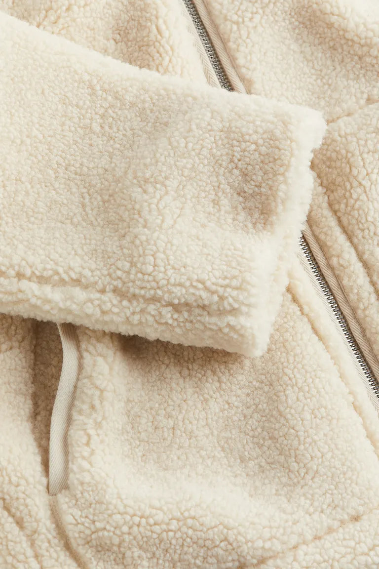 Side profile showing the oversized drop shoulder silhouette and ribbed cuffs of the fleece jacket