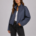 Woman wearing navy polka dot bomber jacket with stand collar and zip-up front over white top