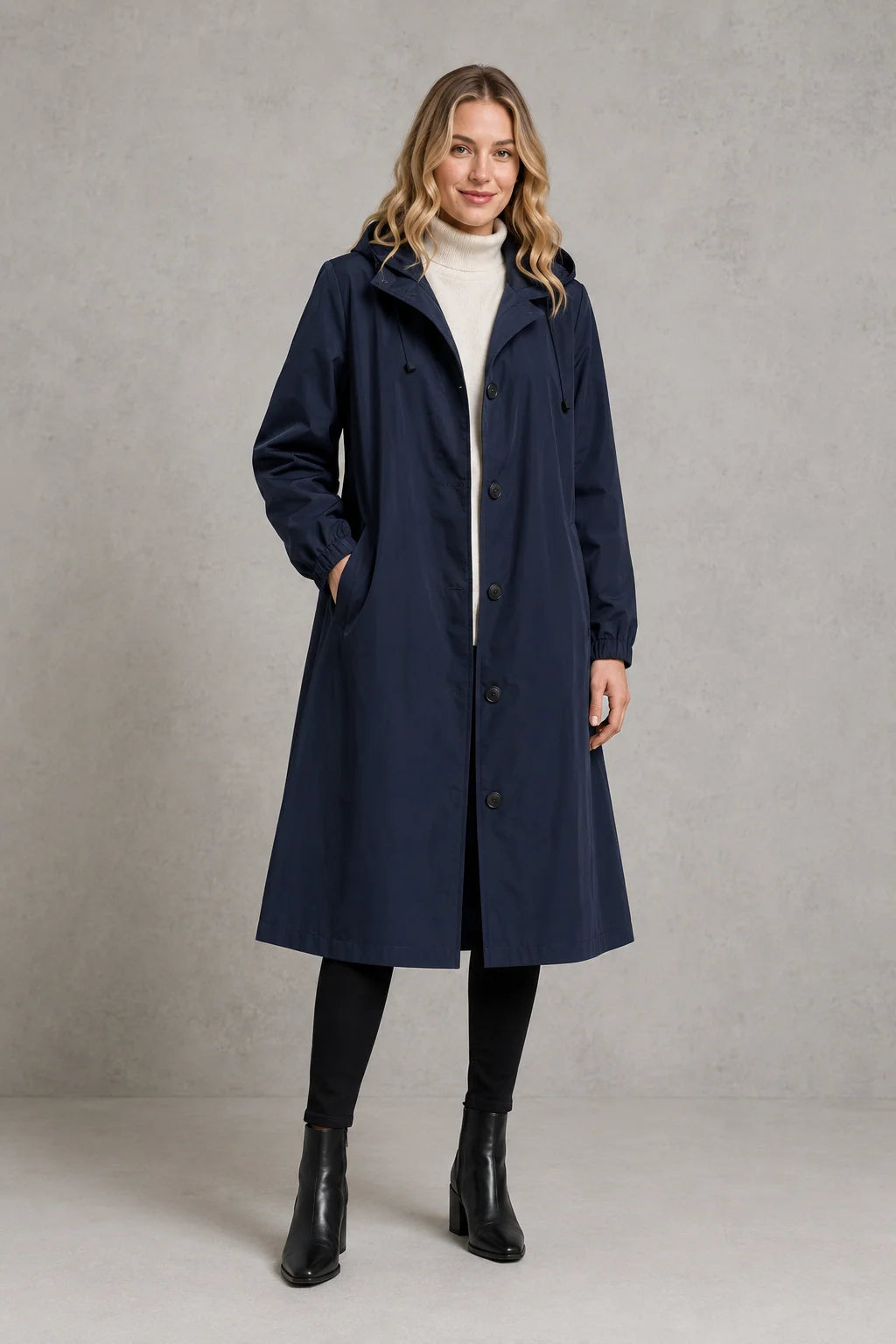 Women's hooded trench coat in light grey layered over cream jumper for spring outfits