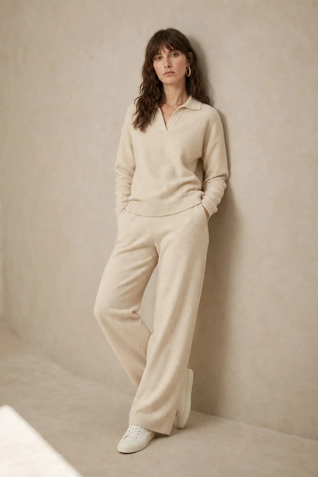 Woman seated wearing beige Merino lounge set showing relaxed silhouette and polo collar design