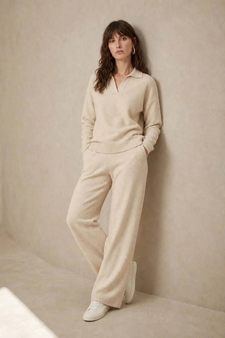 Woman seated wearing beige Merino lounge set showing relaxed silhouette and polo collar design