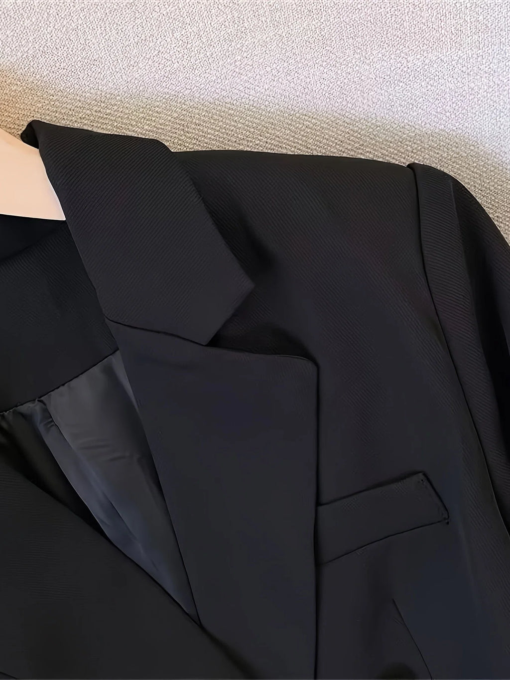 Side view of women's tailored blazer featuring long sleeves with decorative button cuffs