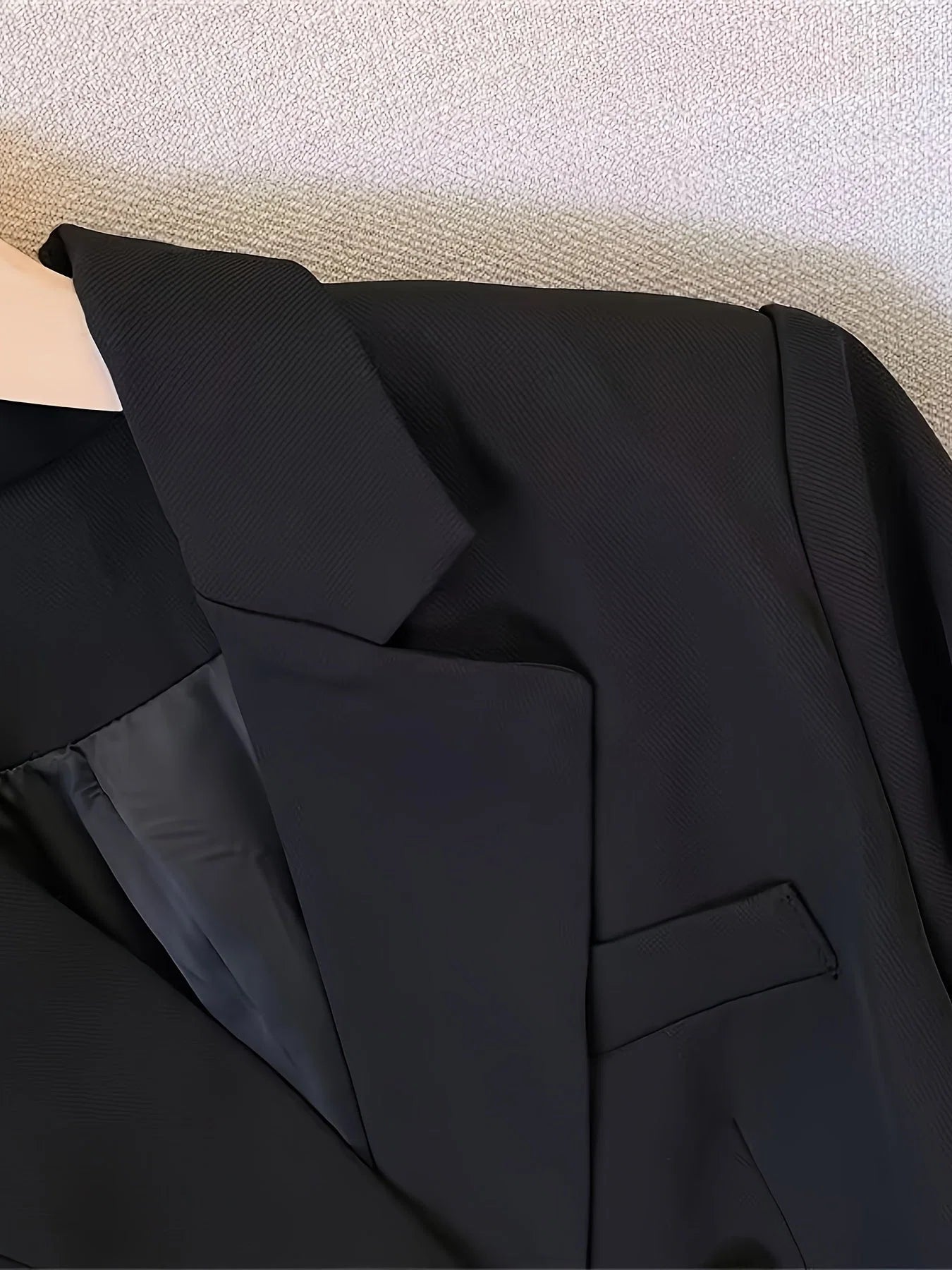 Side view of women's tailored blazer featuring long sleeves with decorative button cuffs