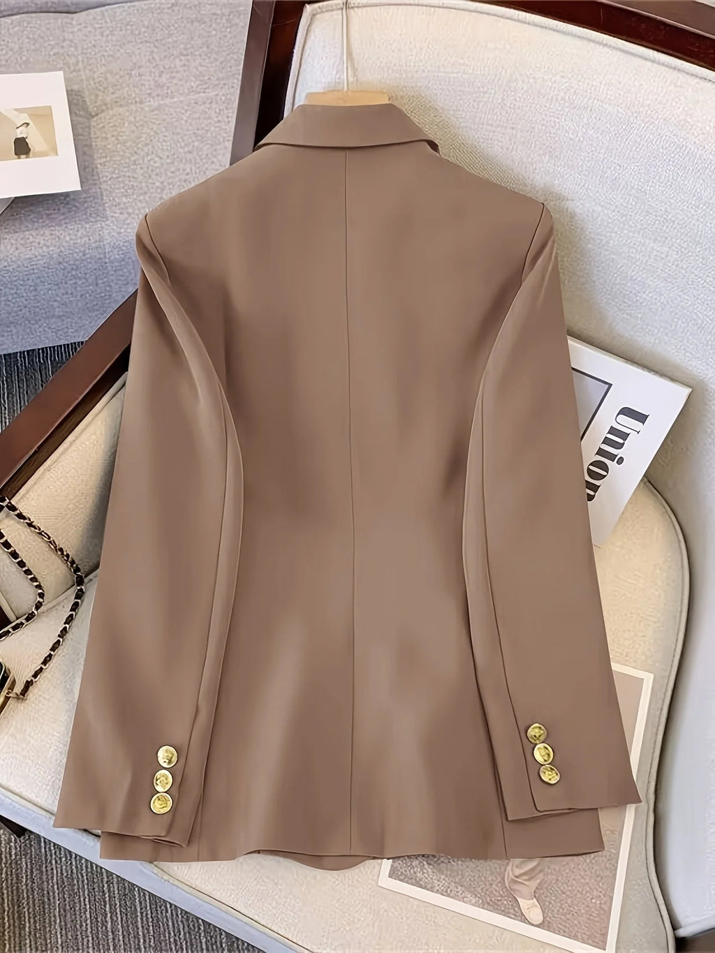 Women's black blazer with gold-tone buttons positioned flat showing overall construction
