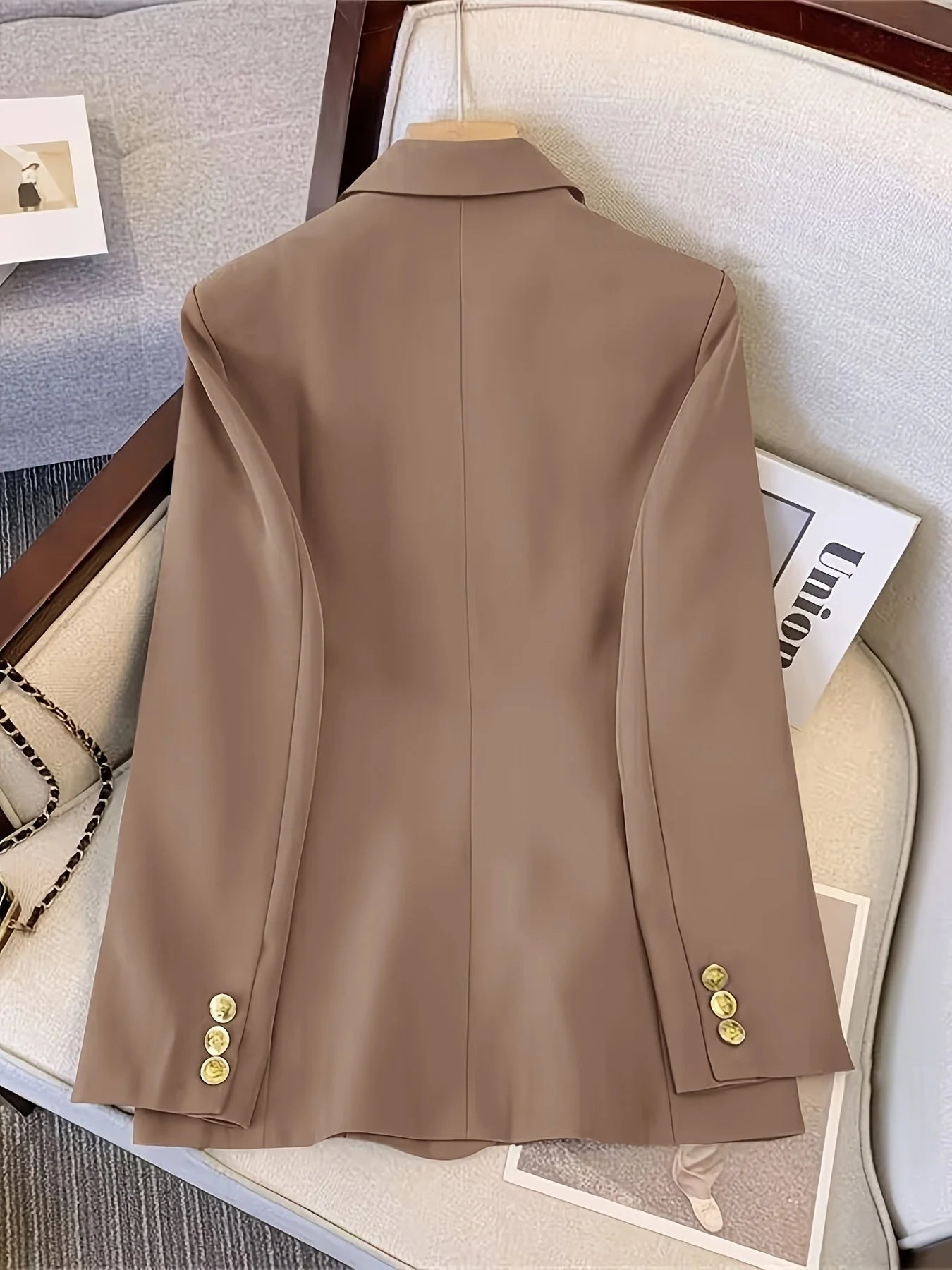 Women's black blazer with gold-tone buttons positioned flat showing overall construction