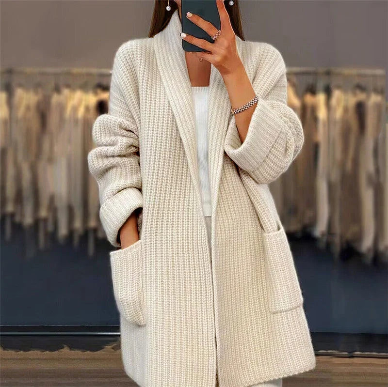 Woman wearing beige oversized knit cardigan with open front and deep pockets over white top